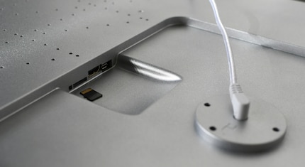 Auf der Rückseite befindet sich ein Slot für eine Speicherkarte. Der Rahmen hat im Unterschied zu einem PC-Bildschirm nur ein dünnes weisses Kabel.