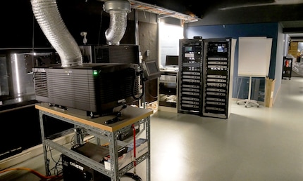 Projecteurs et ordinateurs. La salle est plus grande qu’il n’y paraît. Il s’agit à dire vrai d’un couloir à la fois long et large reliant toutes les salles de cinéma entre elles.