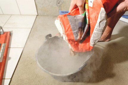 Versa la polvere di colla per piastrelle nel secchio.