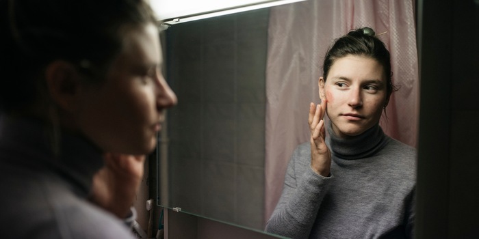 Carla applique de la betterave séchée et pulvérisée avec ses mains. Elle sert de fard à joues naturel.