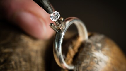 Ein Diamant mit Brillantschliff wird in die Ringfassung eingesetzt.