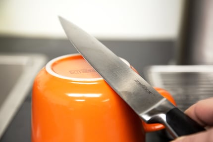 Affila la lama del coltello su entrambi i lati, passandola un paio di volte sulla parte grezza della ceramica.