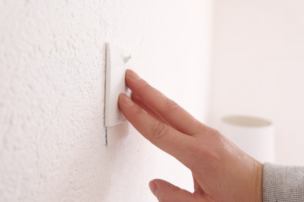 Next, I place the adhesive strips on the wall by pressing on them.