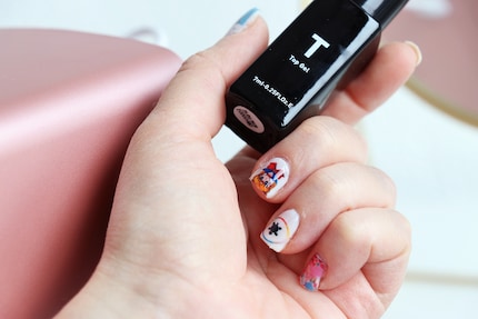 Der Top Coat hüllt die Nägel in einen schönen Glanz und versiegelt das Design.