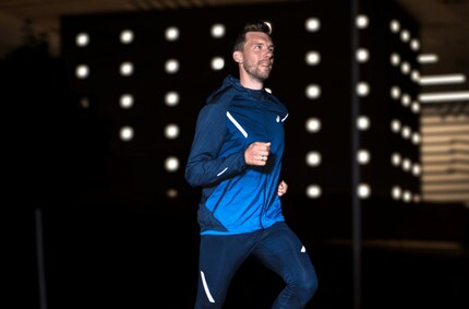 L'atleta modello Asics mostra come le strisce riflettono la luce. Qui l'uomo indossa una giacca della stessa serie.