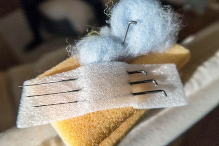 De la laine, une aiguille et une éponge de cuisine en tant que support.