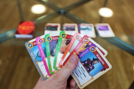 In primo piano, le sette carte in mano. Sullo sfondo, il mazzo e le carte girate.