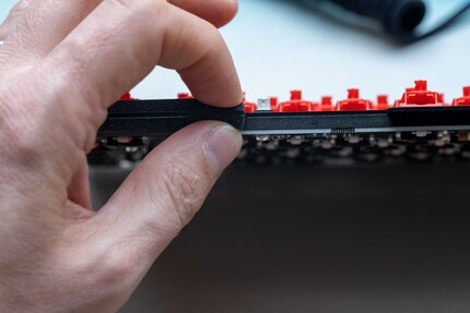 Un tapis isolant se trouve entre la partie supérieure du boîtier et le circuit imprimé. Entre mes doigts, vous pouvez voir les joints qui rendent la frappe flexible.