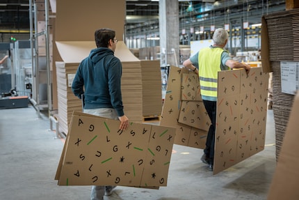 Aurel und Geri verteilen die neuen Kartongrössen in der Logistik.