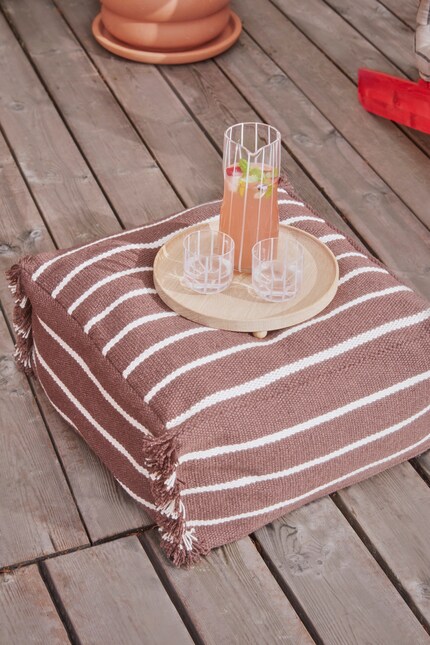 Doté de fines rayures blanches et caramel, le pouf « Lina » s’adapte aux tons naturels dans n’importe quel intérieur.
