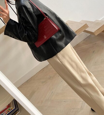 Die dunkelrote Tasche bringt Spannung rein, ohne unruhig zu wirken.