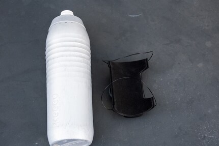 Thread the water bottle through the two laces and tighten by turning the knob.