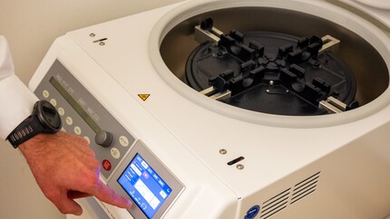 Le docteur règle la centrifugeuse sur cinq minutes.