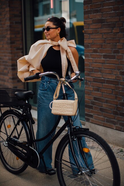 Lo stravagante top asimmetrico con maniche a sbuffo e il fiocco conferisce ai jeans e alla canottiera aria di festa.