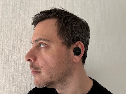 Un badge large et rond dépasse de mon oreille