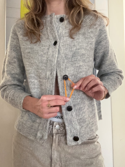 Gummi um den Knopf legen und wie gewohnt zuknöpfen.