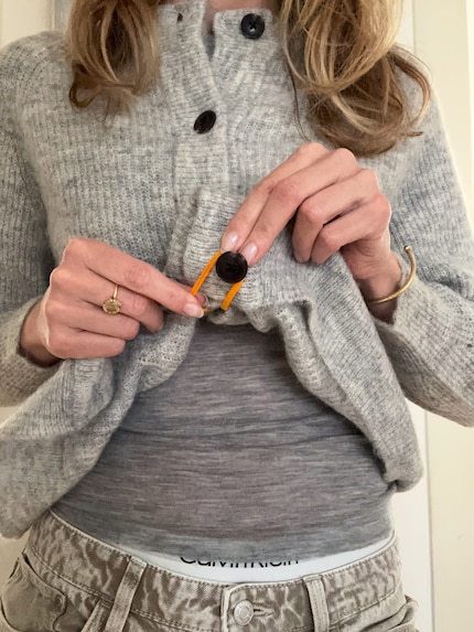 Den Saum nach innen klappen und den letzten Knopf dort am Gummi fixieren.