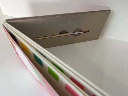 Un petit compartiment à pinceau (0,5 x 12 cm) est caché au dos du bloc.