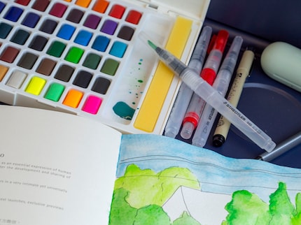 Ik pak in mijn rugzak: waterpenseel, aquarelverfdoos, schetsboek en fineliner. 