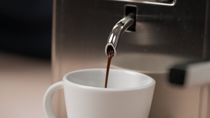 Schwarz und stark läuft der Espresso in die Tasse.