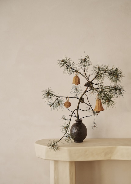 Ein schlichter Zweig wird dank Weihnachtsschmuck dekorativ.
