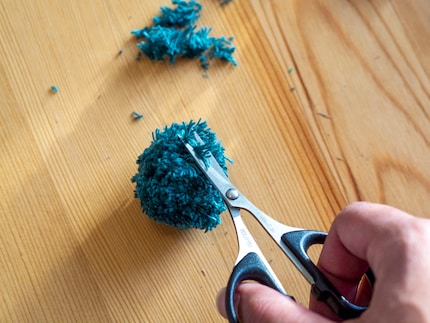 Mit der Schere stutze ich den Wollknäuel zurecht.
