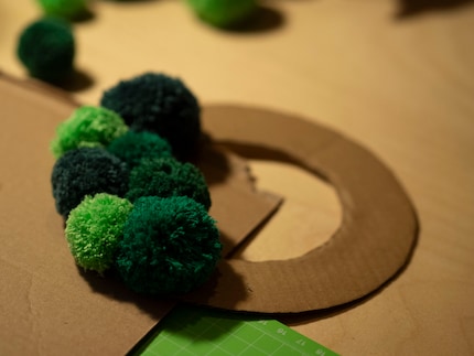 Die Pompons platziere ich auf dem Karton, bevor ich sie festleime.
