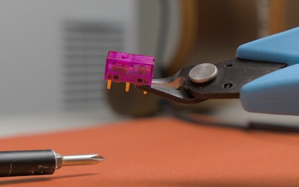 Oben auf dem Schalter, eher links, siehst du den Druckpunkt. Du musst den Pin am weitesten davon entfernt abtrennen, dort, wo der Seitenschneider kontaktiert.