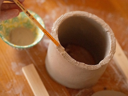 Bepinsle den oberen Rand mit Schlicker, nachdem du ihn eingeritzt hast.