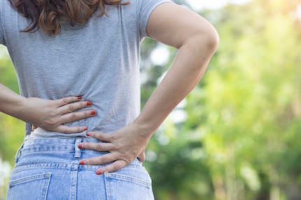 Langes Sitzen oder monotone Alltagsbelastungen gehören zu den typischen Auslösern für Schmerzen im unteren Rücken.
