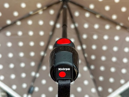 Einfach den roten Knopf drücken und der Schirm springt auf beziehungsweise zu.