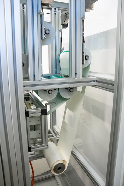 Nach dem Siegelprozess stanzt die Anlage die Form der Vierrandbeutel aus der Papierbahn. In der aufgewickelten Papierbahn sind diese Ausschnitte deutlich zu erkennen – wie ausgestanzte Formen in einem großen Papierbogen.