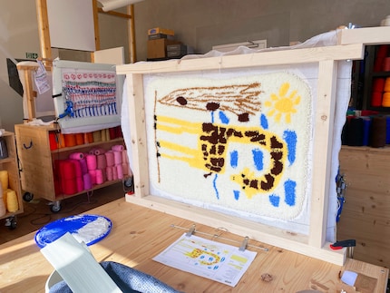 Hier legt die Tochter einer Mitarbeiterin selbst Hand an und tuftet sich im sozialen Atelier in Wangen bei Olten einen Teppich aus ihrer Giraffen-Zeichnung.