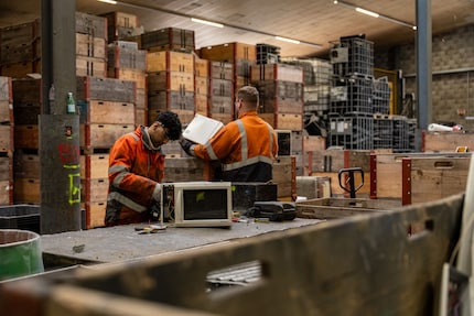 Diese zwei Mitarbeiter zerlegen Mikrowellen für die weitere Bearbeitung.