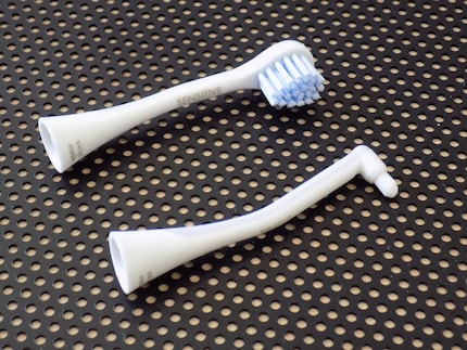 Die Aufsätze sind leicht gebogen, ähnlich wie die Instrumente in der Zahnarztpraxis. Die untere Bürste ist für Zwischenräume und Zahnfleischränder gedacht.