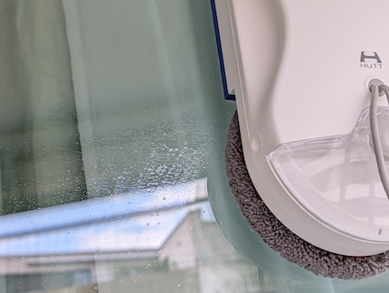Eine Düse bespritzt das Fenster mit Wasser, dann schrubbt der Roboter los.