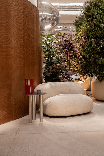 Ein cremefarbener Bouclé-Sessel weicht den Beistelltisch Brandt Small Table von Noom optisch auf.