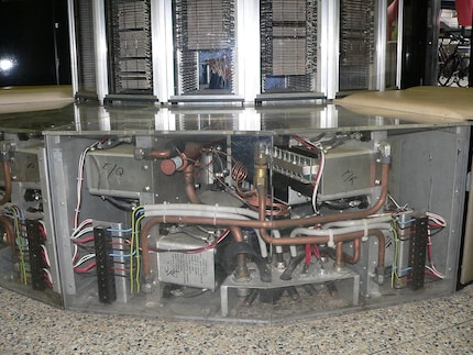 Die freigelegte Technik unter der Sitzbank zeigt unter anderem metallische Gehäuse und Rohrleitungen.