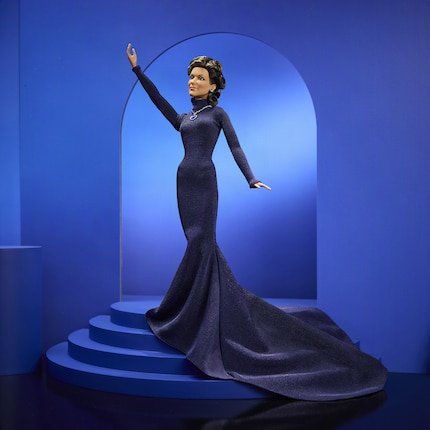 The dark blue dress with a high collar and long train reflects Dion's 1998 stage look.